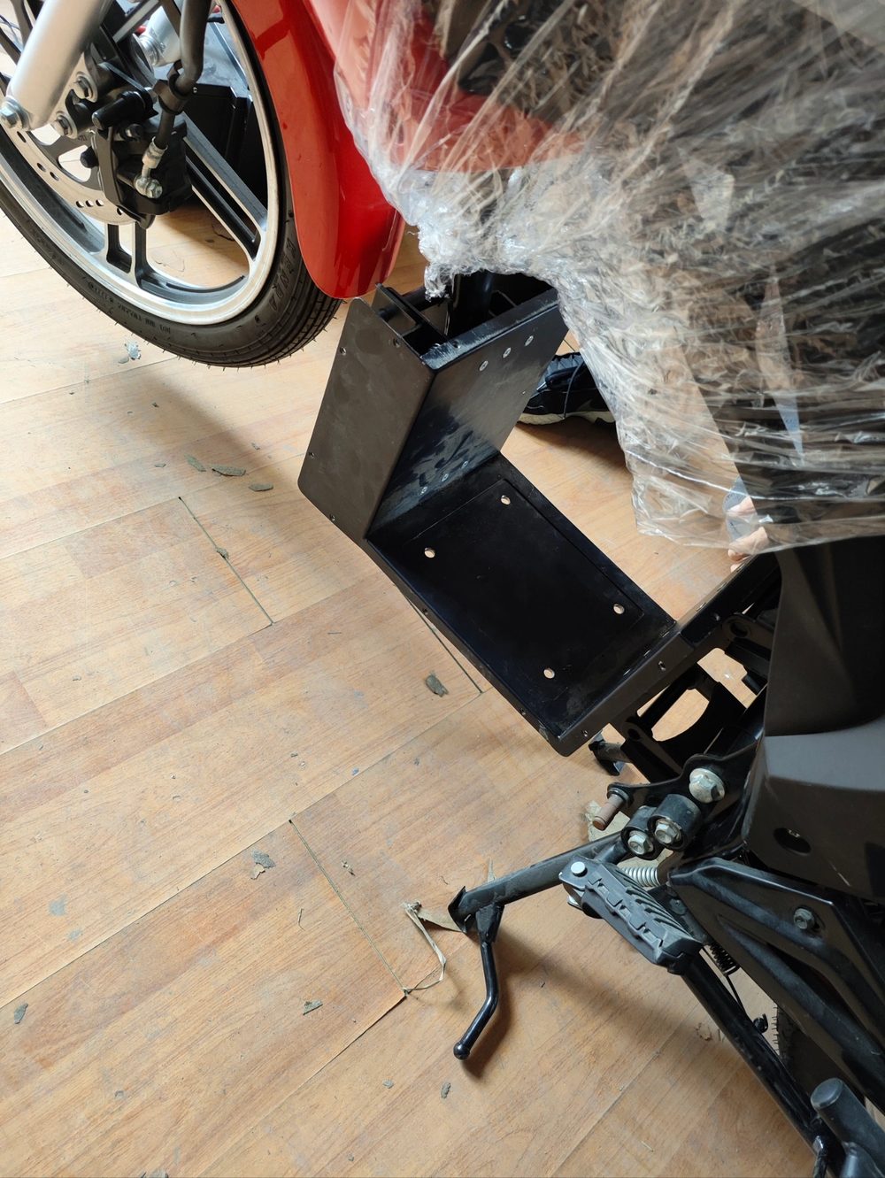 Motorcycle with a custom mounting bracket being measured for the battery case